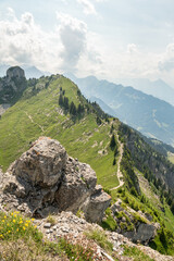 Summer view from Oberschildhorn mountain towards Schynige Platte in the Jungfrau region. Alpine mountains with hiking trail. Rocks in the foreground. Swiss Alps landscape.