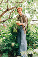 Red hair woman with short haircut in the garden eco style cloth with hydrangea farming gardening people