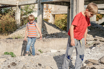 Two poor and dirty children are looking for food and shelter in