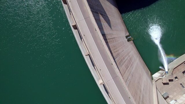 Dam discharging water. Howell bunger valve in operation.  Ascending aerial view with rotation over the dam and river. Renewable energies.