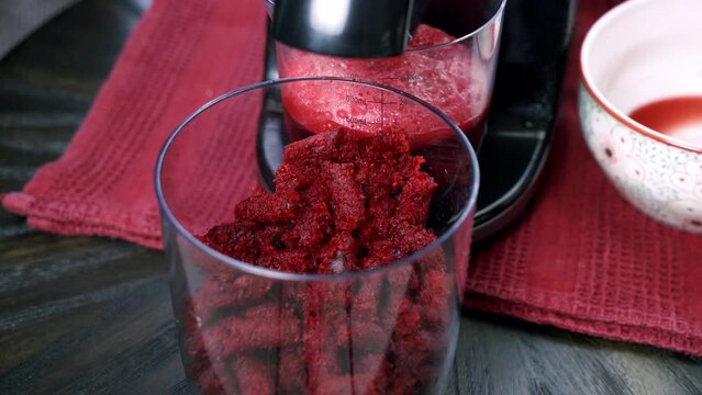 Close up of beets being juiced and beet pulp falling out inside of a container making dessert beet muffin