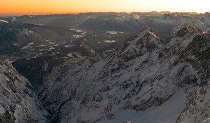 View from the German highest point called Zugspitze mountain down to the Bavarian village Garmisch Partenkirchen and Grainau during sunrise phase