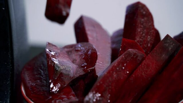 Picking up a piece of beet slice from a bowl of beets to make beet pulp muffins chocolate chip vday muffins