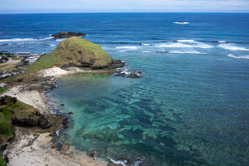 Fototapeta premium Serene Coastal Landscape of Lombok, Indonesia: Aerial View of Crystal Clear Waters and Rugged Shoreline