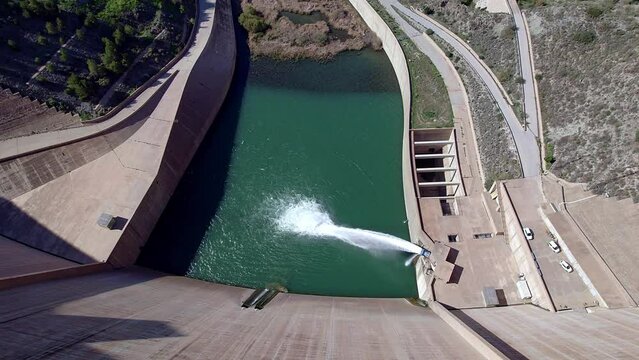 Dam discharging water. Howell bunger valve in operation.  Revealing aerial view of the dam and river. Dolly out aerial view. Renewable energies.