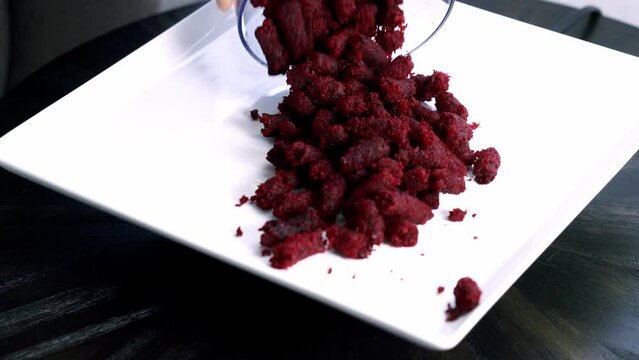 Adding beet pulp muffin pellets into a white plate preparing to make a chocolate beet pulp muffin