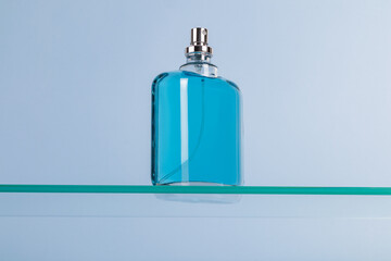 Beautiful glass bottle of cosmetic spray, perfume, eau de toilette on a floating glass surface. Blue background. Product presentation. template.