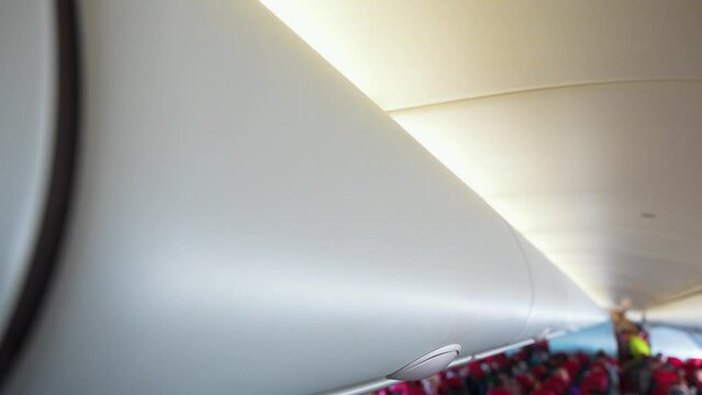 Closing overhead compartment with luggage before airplane flight.