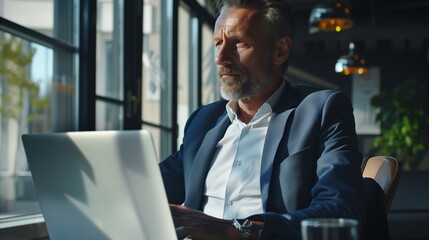 Positive senior bearded man with grey hair using laptop at cafe, copy space. Stylish aged businessman in jacket working online