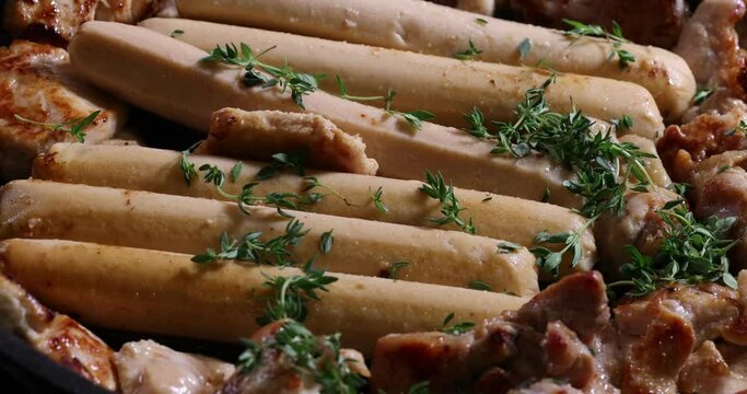Frying skinless small chicken fillet pieces sausage bangers in lightly coated oil thyme herb non stick pan cooking sizzling dark golden brown putting taking serving rolling stir