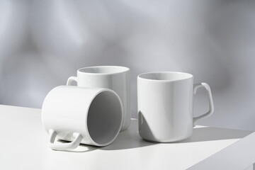 White ceramic mugs on gray background with shadows