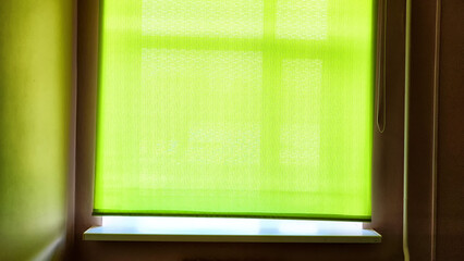 Green Window Shade Casts a Soft Glow in a Dimly Lit Room at Dawn. Background, texture, place for...