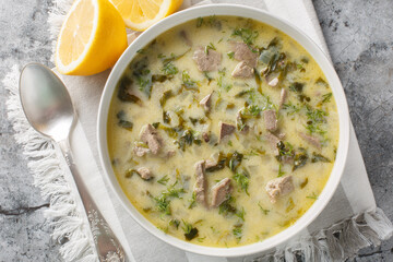 Greek Easter soup with lamb offal, herbs, seasoned with egg and lemon sauce close-up in a bowl on a...