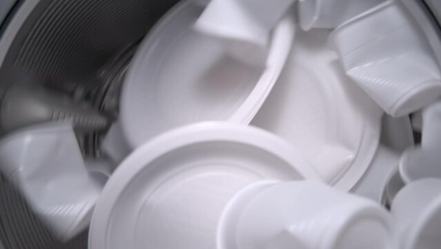 Inside view of the washing machine drum with white food plastic, close-up of the drum during the spin cycle. Concept of recycling plastic and ecology. Plastic waste.