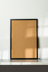 Blank wooden frame mock up on desk near white wall