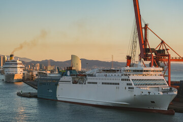 Fototapeta premium Mega LNG powered car, passengers pax and cargo transporter ro-ro ferry ship cruiseship cruise liner in Barcelona port, Spain with harbor and city skyline 