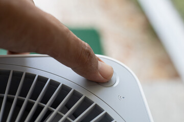 Hand pressing a button for an electrical appliance or air purifier.