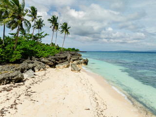 Coconut trees and sandy beach in Carabao Island. Blue sky and clouds. Romblon. Philippines.