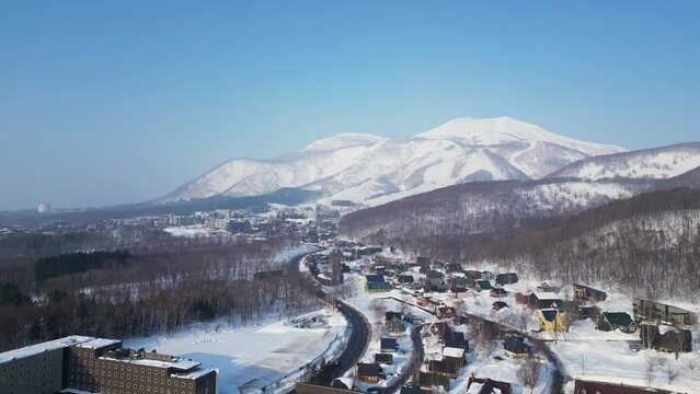 Niseko, Japan: Aerial drone footage of the road leading to the famous Niseko ski resort on a sunny winter morning in Hokkaido island of northern Japan. 