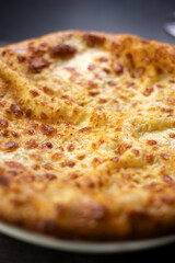 Khachapuri with sulguni cheese on white plate. Megrelian khachapuri, close-up. Concept of traditional georgian cuisine.