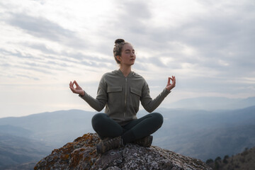 Woman practices yoga and meditates in the lotus position in the mountains, young woman doing yoga, woman yoga - relax in nature