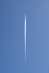 Distant Passenger Jet Plane Flying at High Altitude on a Clear Blue Sky Leaving a White Smoke Trace of Contrail Behind - 752795228