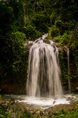 Jungle waterfall cascade in tropical rainforest with rock and turquoise blue pond