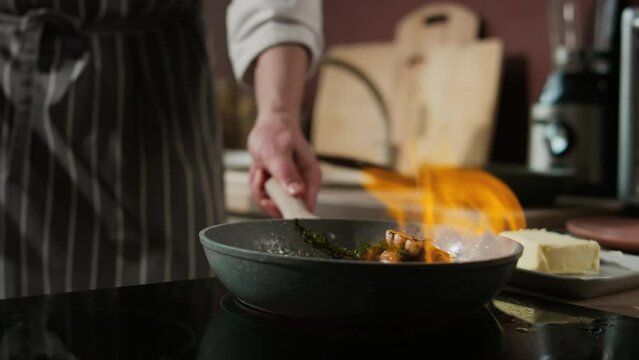 Cropped shot of unrecognizable male chef cooking beef steak on frying pan with fire