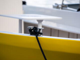 A close up of a fishing boat moored in a harbour, secured by an anchor and rope to a dock bollard....