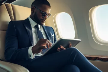 Gartenposter black businessman in glasses using a tablet on the plane © Ceric Jasmina