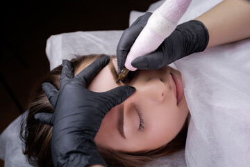 Completing permanent eyebrow makeup with a tattoo machine. PMU Procedure, Permanent Eyebrow Makeup.
