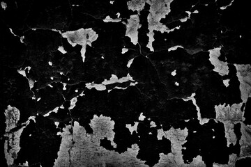 Peeling black and white paint on the concrete wall with old cracked flaking paint. Weathered rough painted surface with patterns of cracks and peeling texture for background 