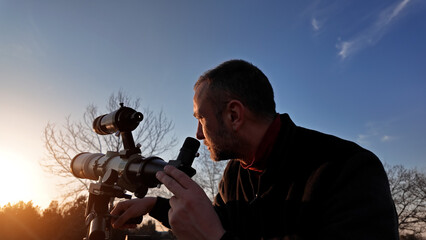 Amateur astronomer observing Sun eclipse and Sun with a telescope and special solar filter.