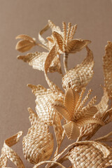 Obraz premium Decoration of straw on a beige background. Branch with leaves and flowers is made of straw. Decor. Closeup