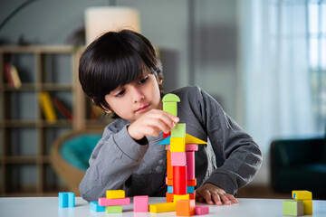 Indian asian boy playing with colourful toy blocks at home.