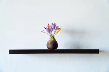 Fotobehang first spring flowers crocus in vase on a shelf at home © Natalia Navodnaia