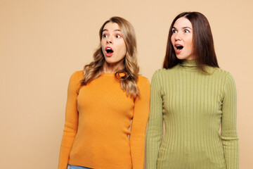 Young shocked surprised friends two women wear orange green shirt casual clothes together look...