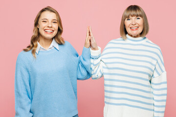 Elder parent mom 50s years old with young adult daughter two women together wearing blue casual clothes meeting together greeting giving high five isolated on plain pink background Family day concept