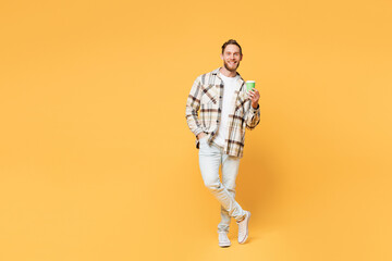 Fototapeta na wymiar Full body young Caucasian man wear brown shirt casual clothes hold takeaway delivery craft paper brown cup coffee to go isolated on plain yellow orange background studio portrait. Lifestyle concept.