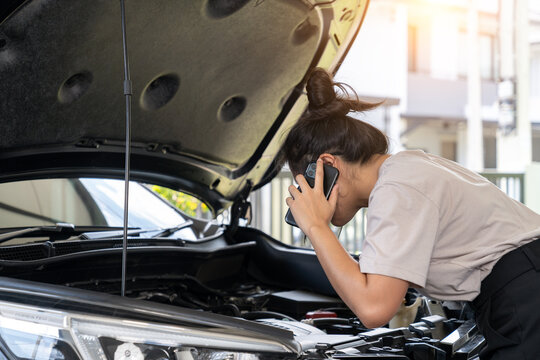 The young woman is calling for assistance because her car is broken down