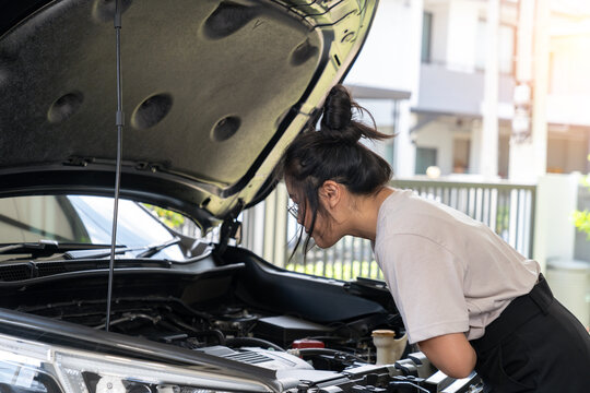 The young woman is calling for assistance because her car is broken down