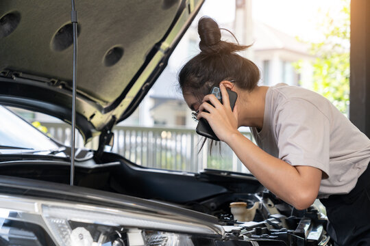 The young woman is calling for assistance because her car is broken down