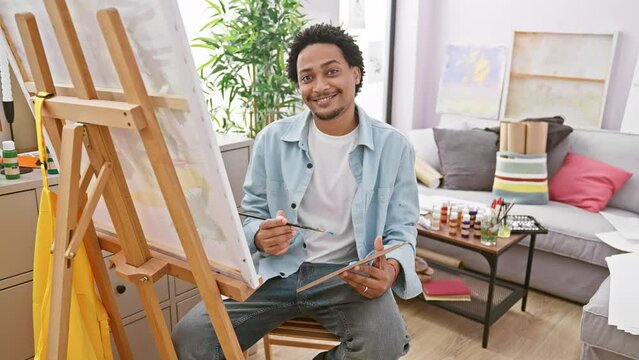 Smiling man painting in a bright art studio, showcasing creativity and casual indoor leisure activity.