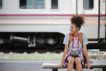 Young Asian African woman traveler with backpack in the railway train station, traveler girl walking stand sit waiting take a picture on railway platform train station. High quality photo