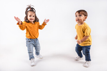 A two-year-old boy and girl dancing happily and animated on white background