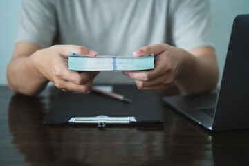 A man holds a banknote with a computer next to it. Concepts of finance, investing, saving money or taxes. Illustrations about finance, banking.