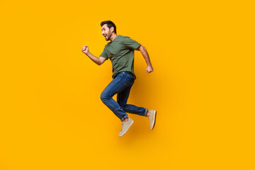 Full size photo of handsome young guy running hurry big sales dressed stylish khaki outfit isolated on yellow color background