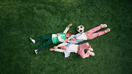 Lying down. Kids are having fun on the green soccer field together