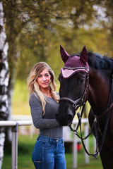 Obraz premium Young woman with long hair and blonde streaks, stands portraits with her horse.