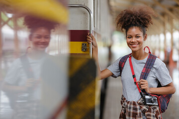 Young Asian African woman traveler with backpack in the railway train station, traveler girl...